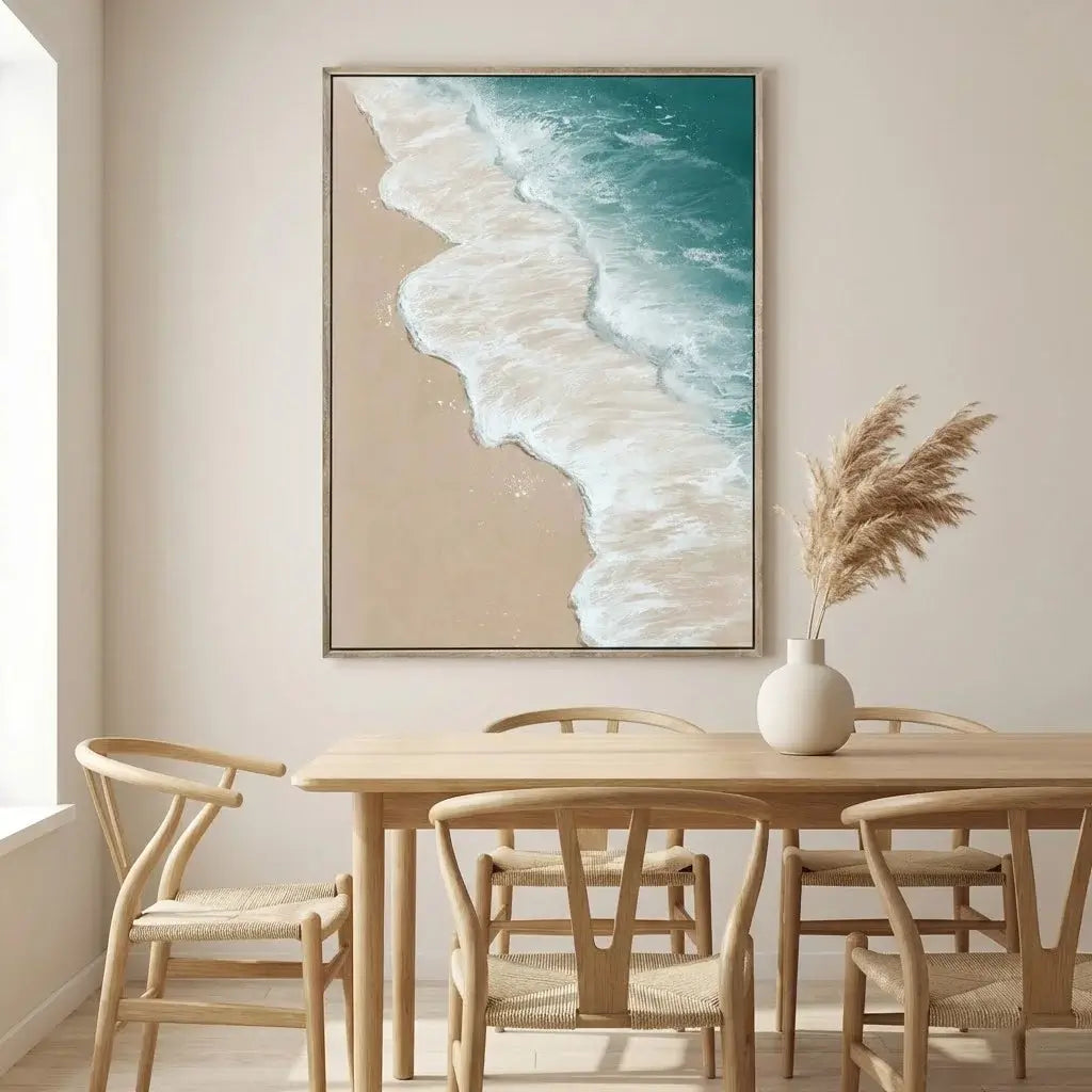Dining room with a table and chairs, a vase with dried plants, and a large framed artwork of a beach scene on the wall.