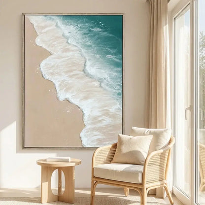Beach scene painting on a wall above a wicker chair with cushions in a bright room.