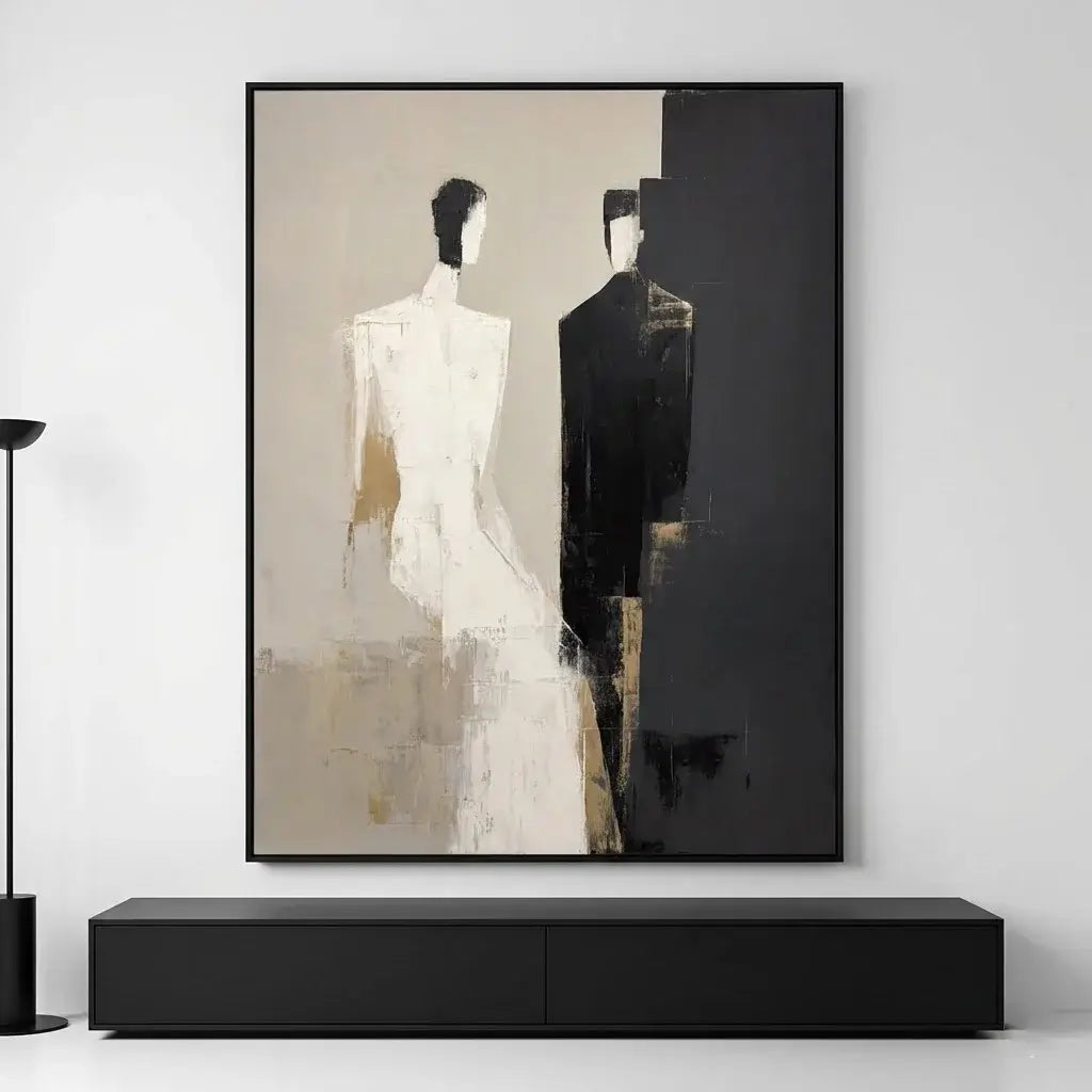 Abstract art piece with two figures in a black frame on a white wall.
