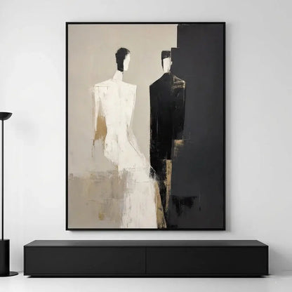 Abstract art piece with two figures in a black frame on a white wall.